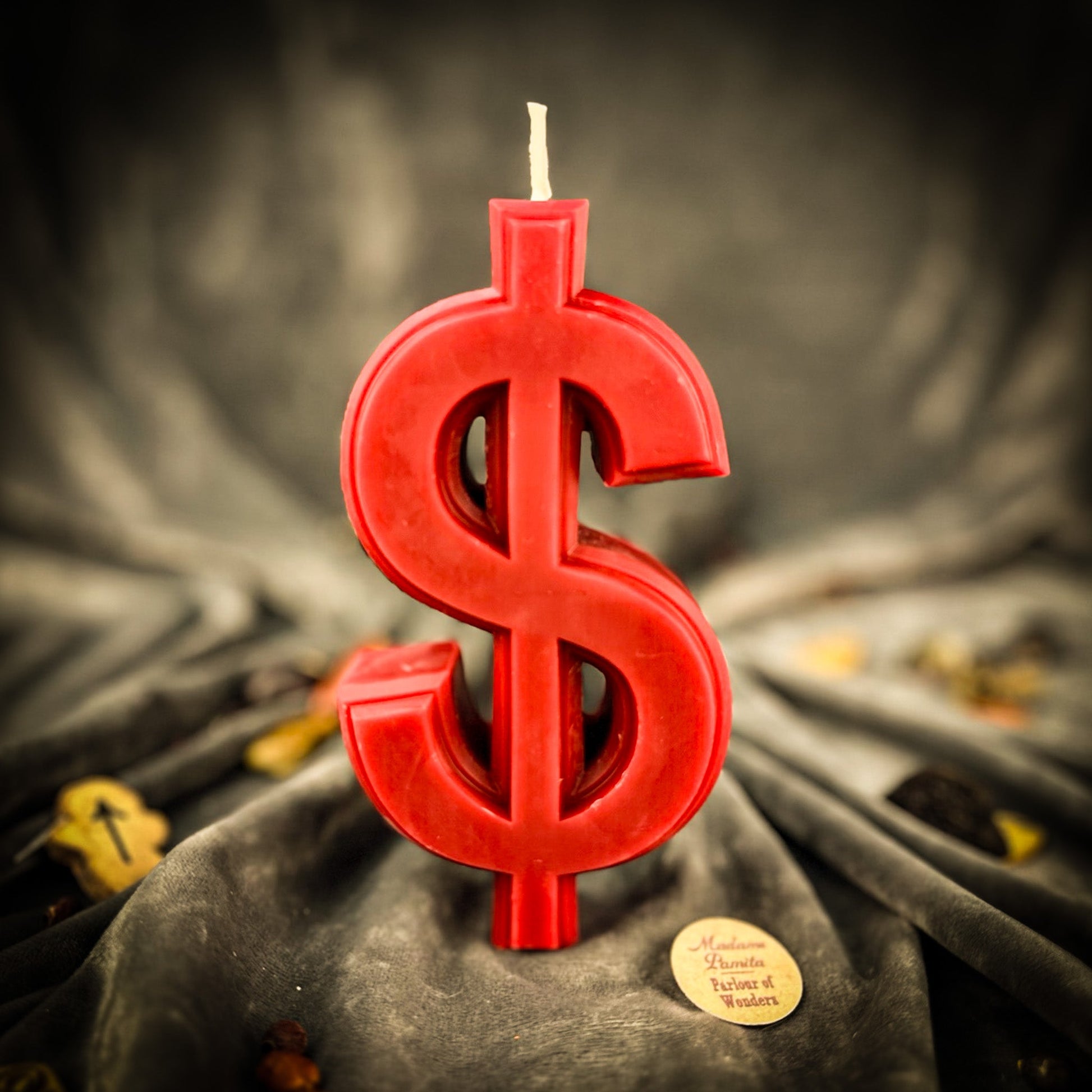 Red dollar sign candle on a dark fabric background