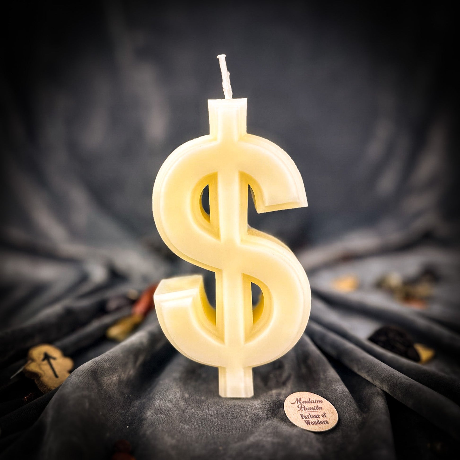 Candle shaped like a dollar sign on a dark fabric background