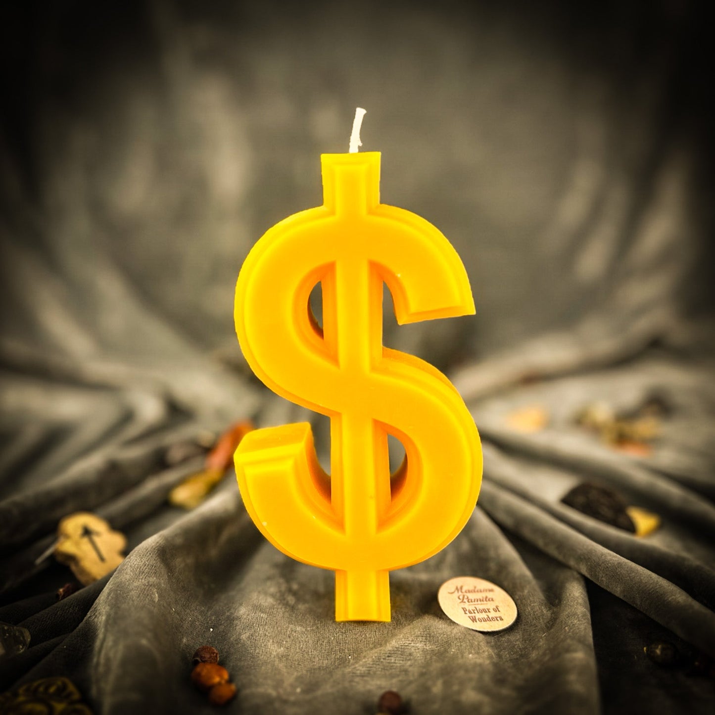 Yellow dollar sign candle on a dark fabric background
