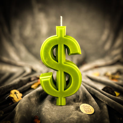 Green dollar sign candle on a dark fabric background