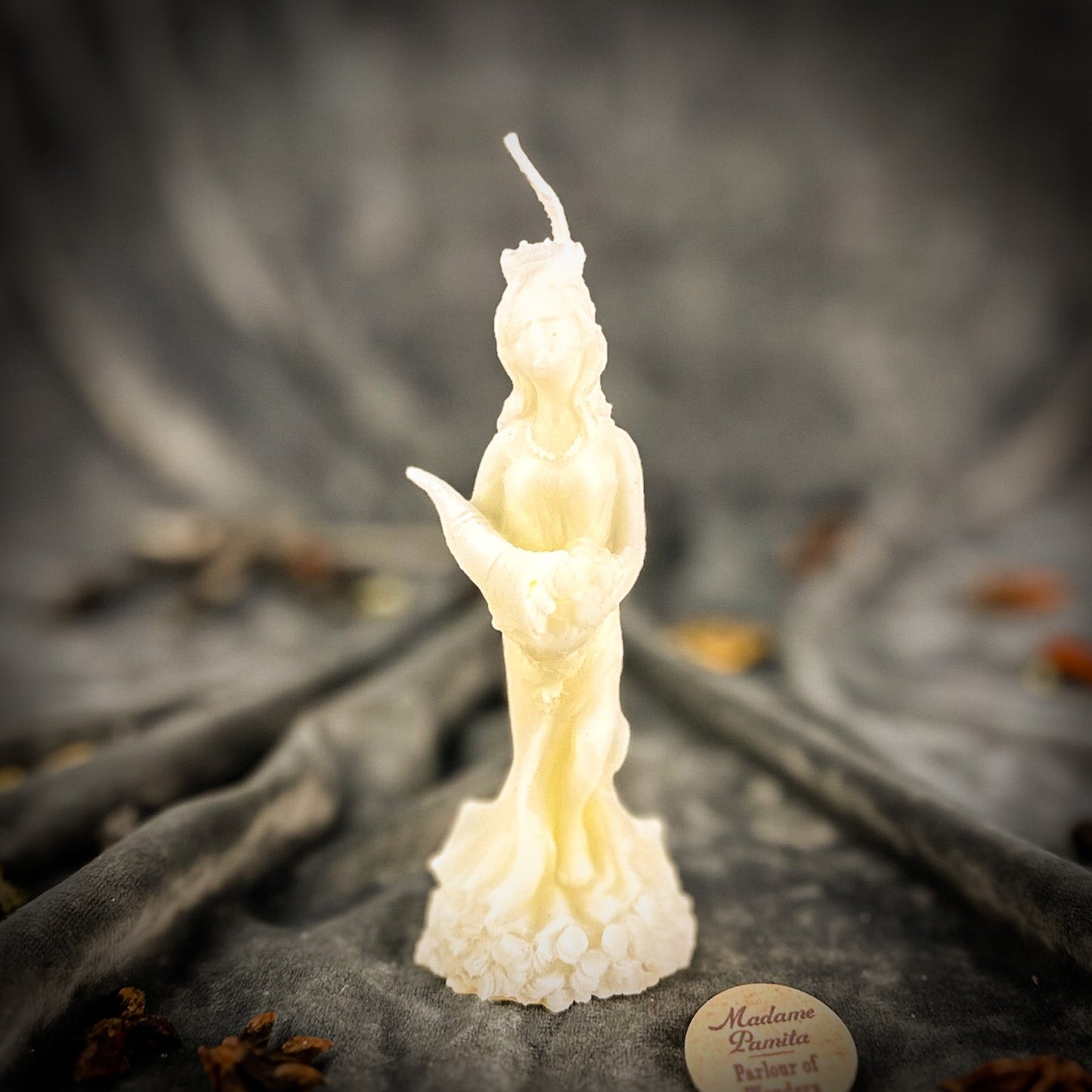 Candle shaped like a figure on a textured surface with a blurred background