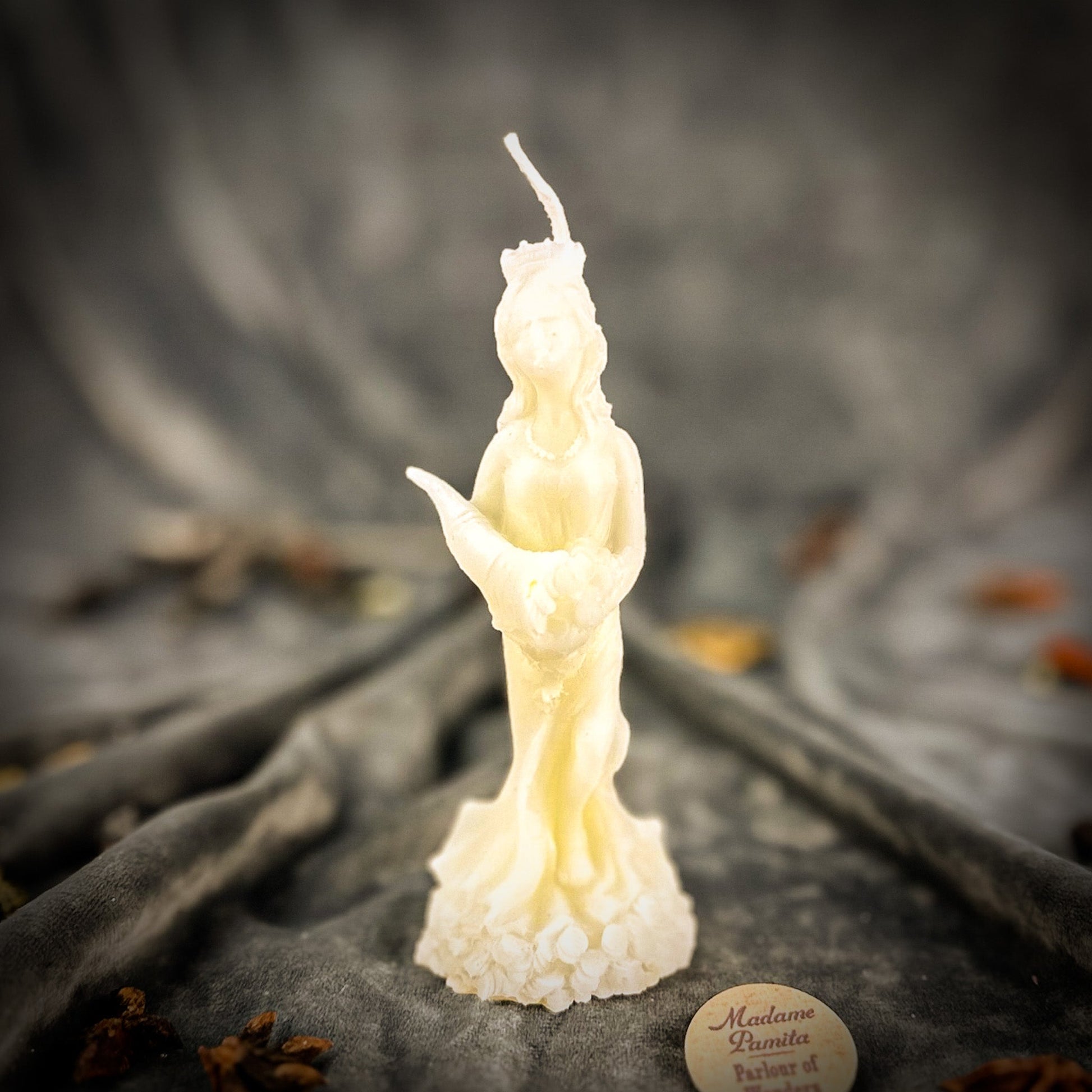 Candle shaped like a figure on a textured surface with a blurred background