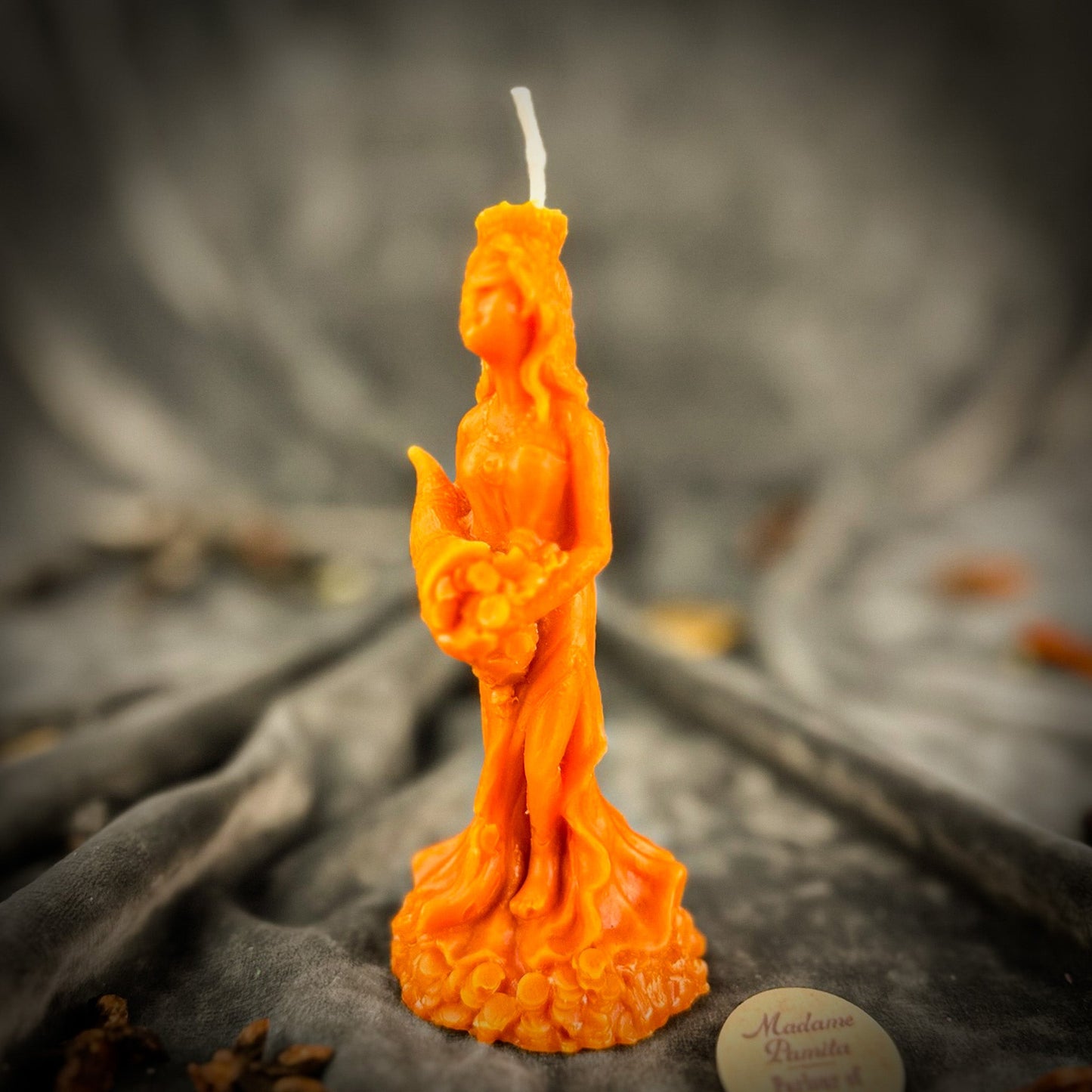 Orange candle shaped like a woman on a dark textured surface