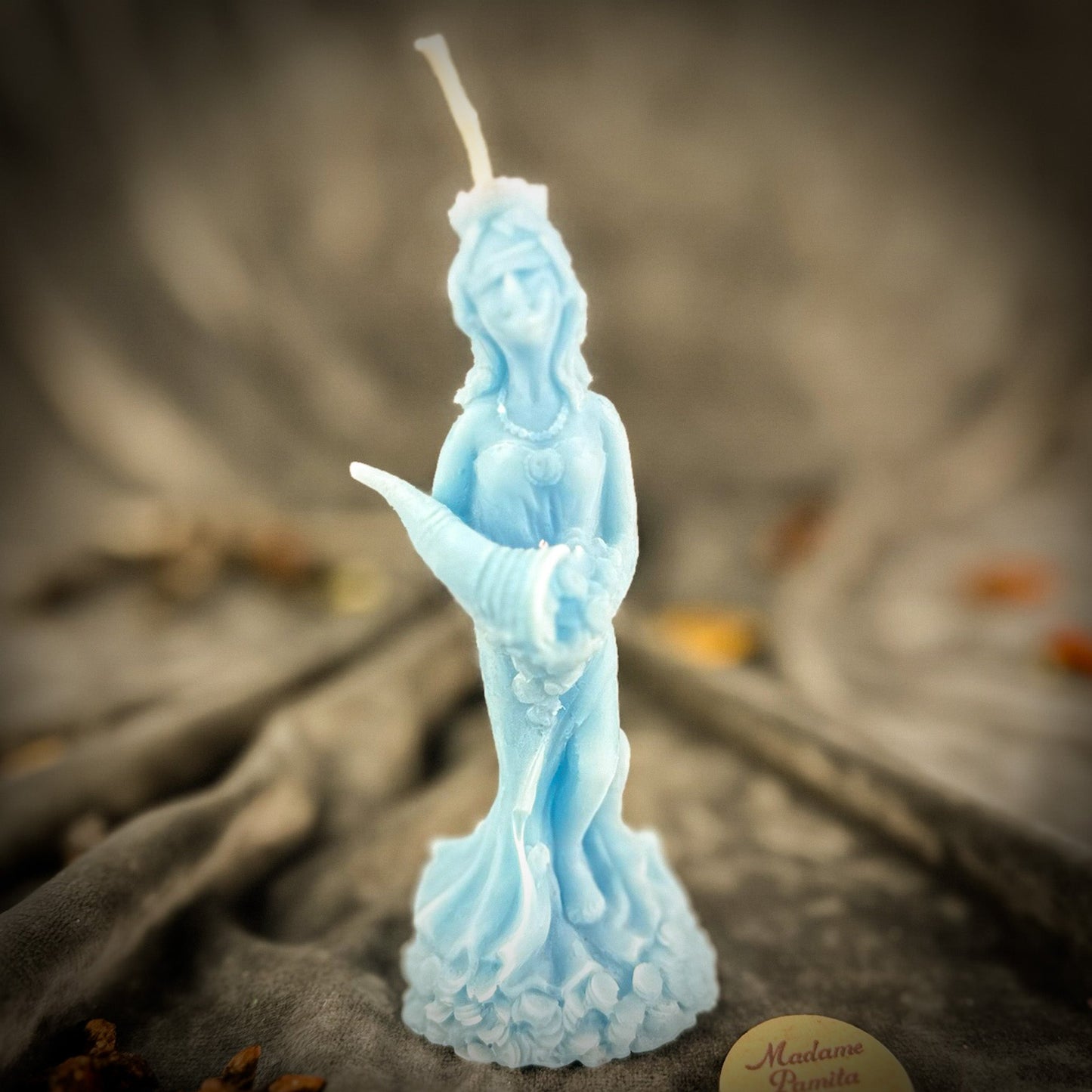 Blue statue-shaped candle on a textured surface with a blurred background