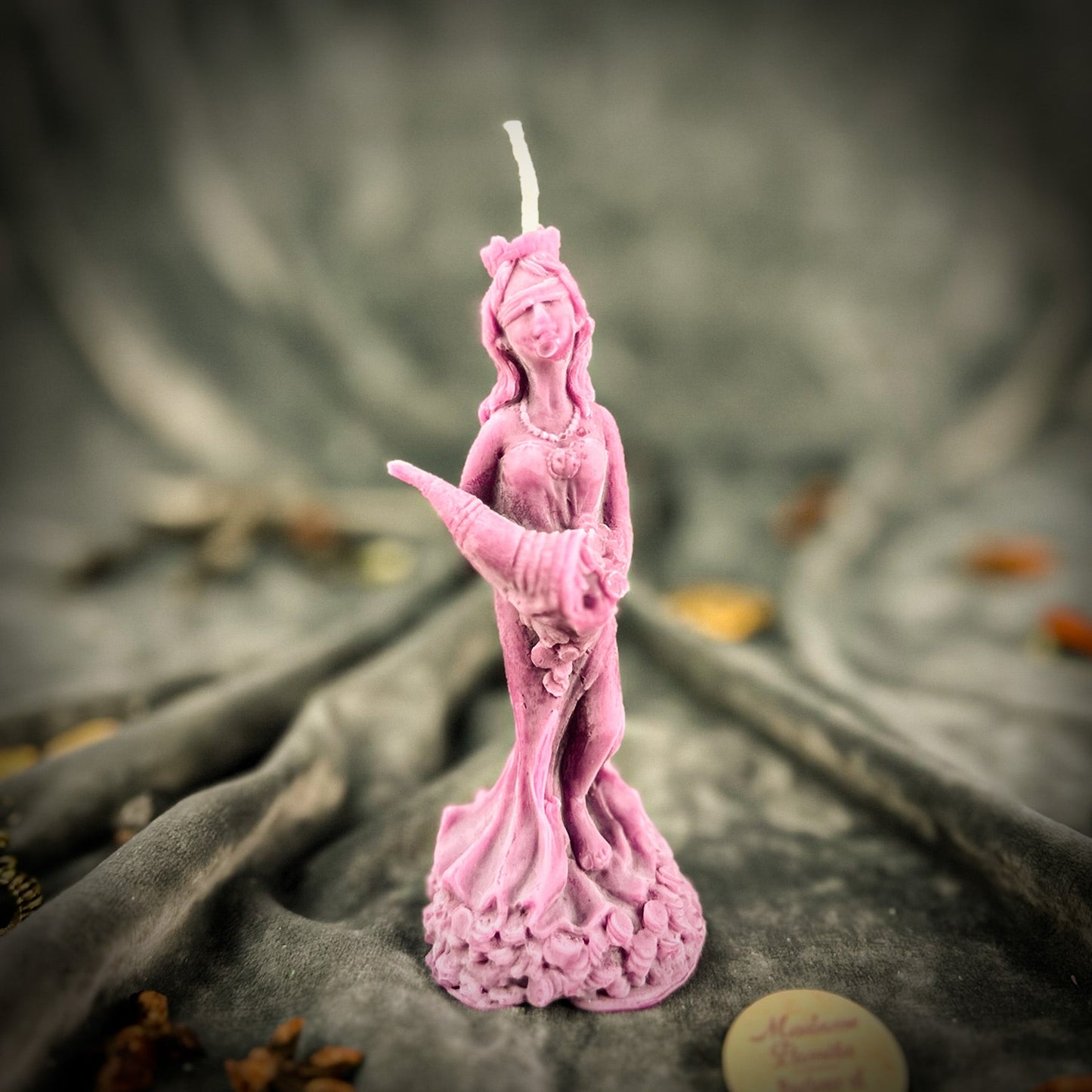 Pink statue candle on a textured surface with blurred background