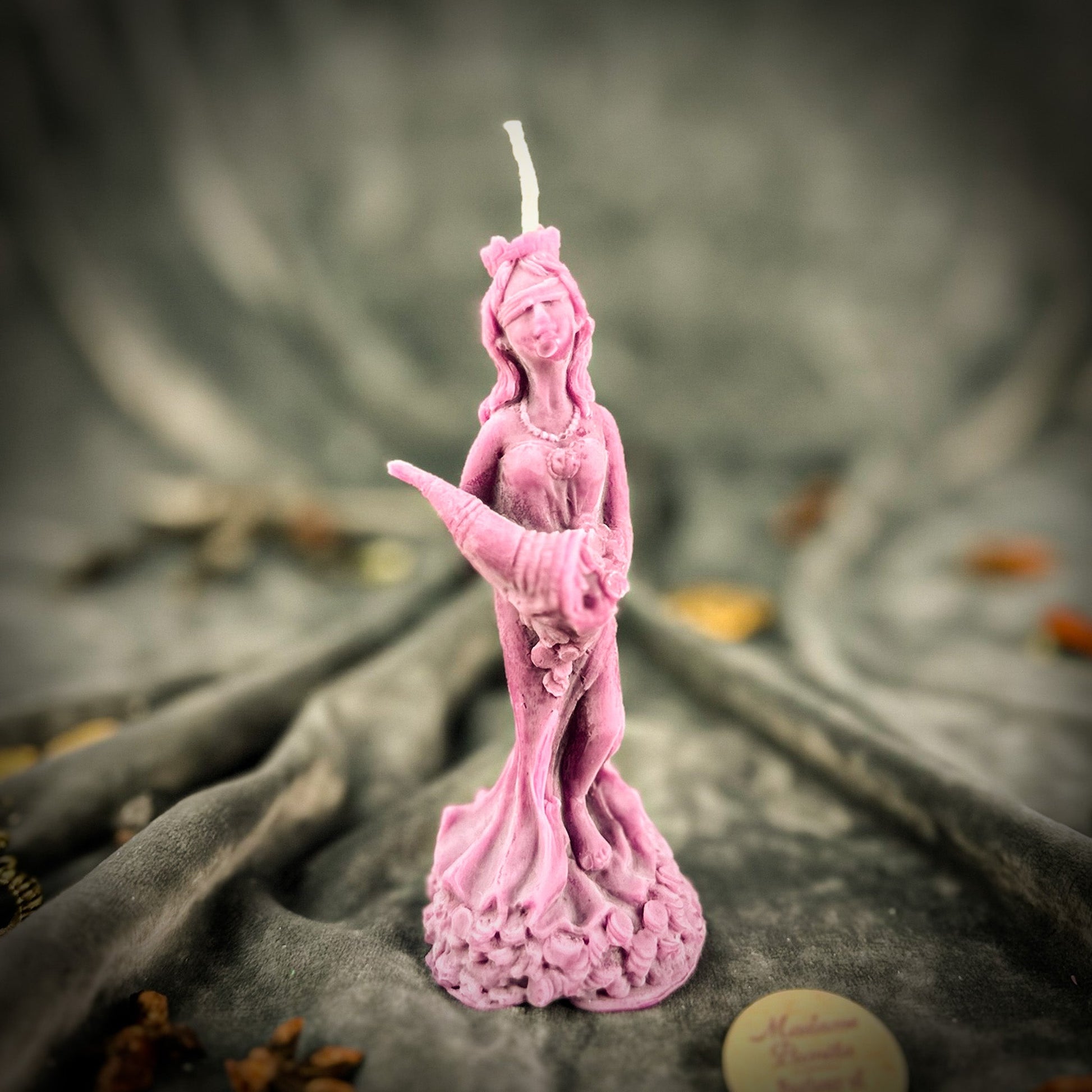 Pink statue candle on a textured surface with blurred background