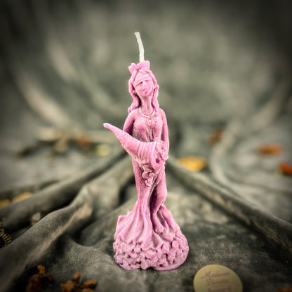 Pink statue candle on a textured surface with blurred background