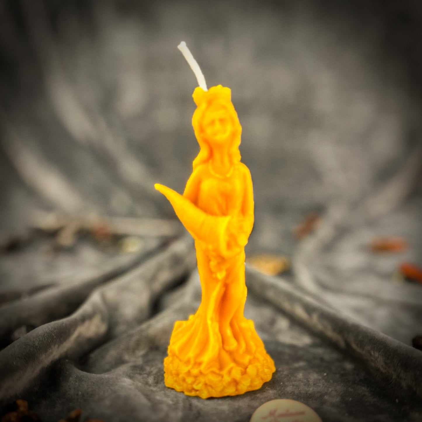 Yellow candle shaped like a person on a dark fabric background