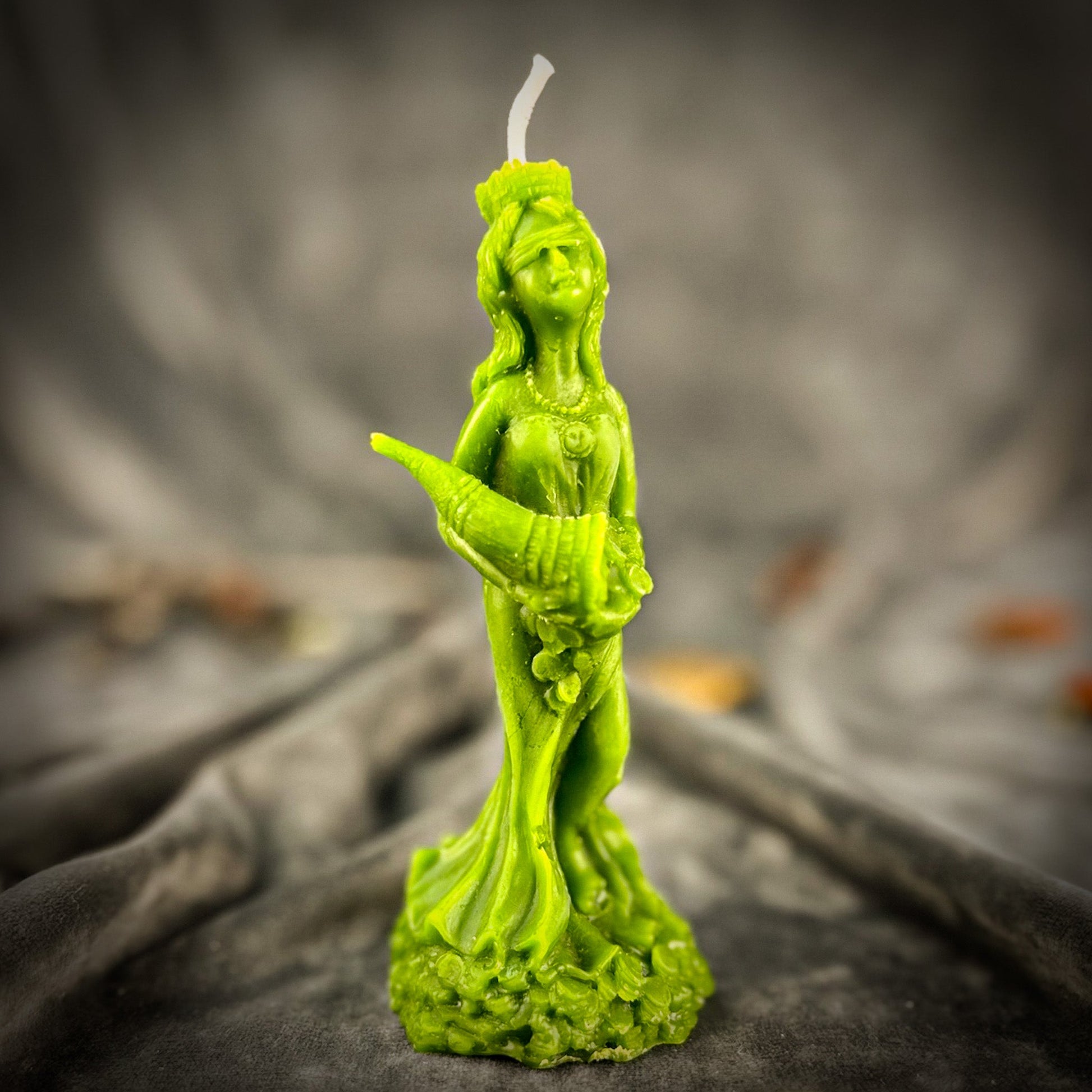 Green figurine candle on a dark textured surface