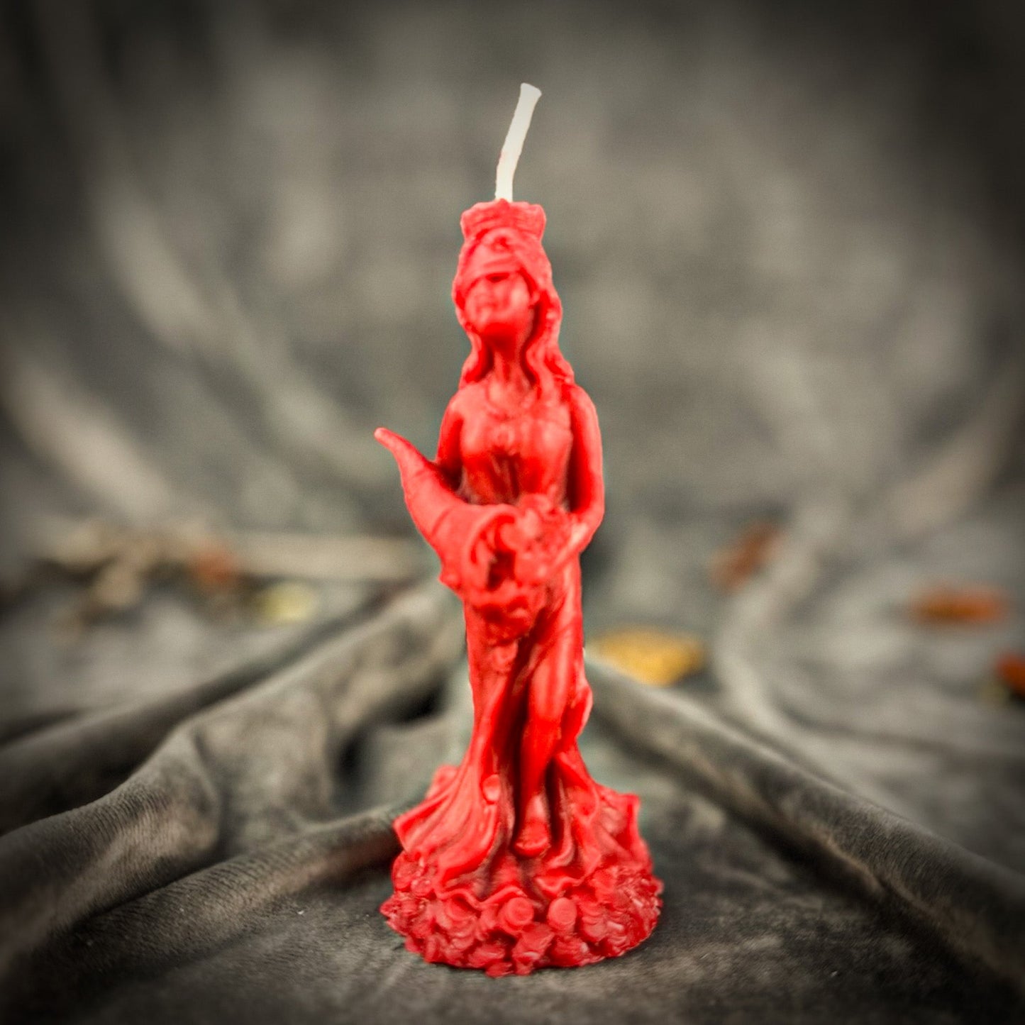 Red statue-shaped candle on a dark fabric background