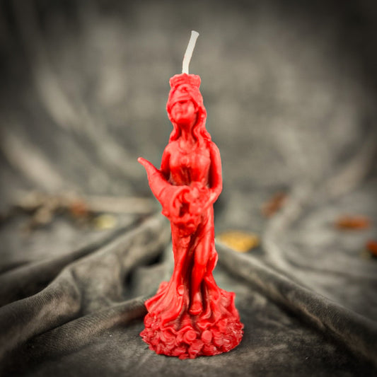 Red statue-shaped candle on a dark fabric background