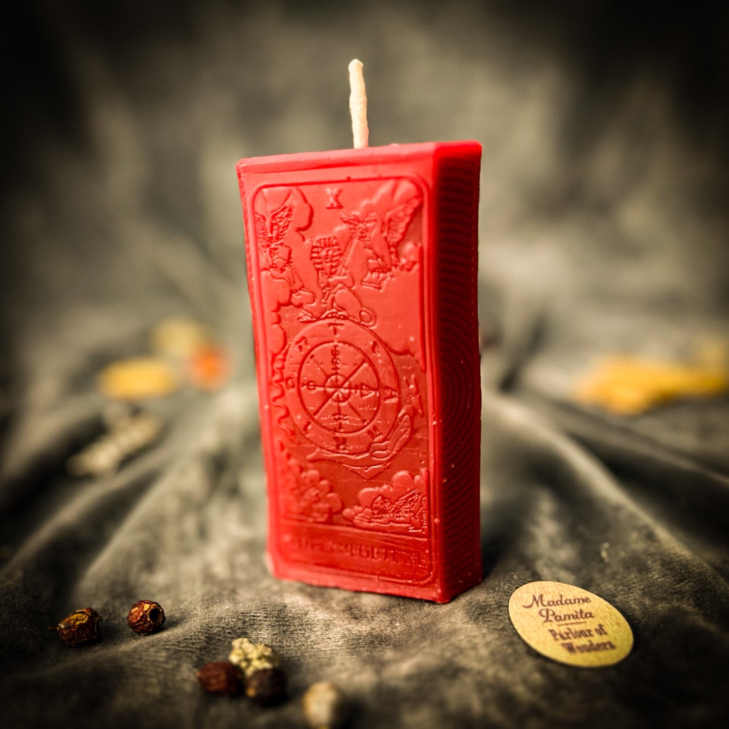 Red embossed candle on a dark fabric background with a blurred background
