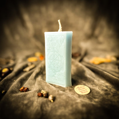 Light blue candle with textured design on a dark fabric background