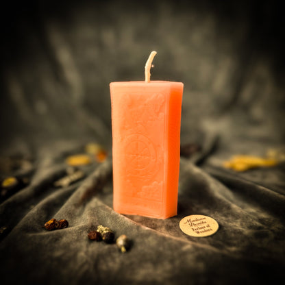 Rectangular pink candle with an embossed design on a dark fabric background