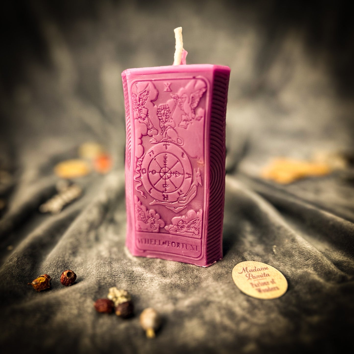 Pink rectangular candle with intricate designs on a dark fabric background