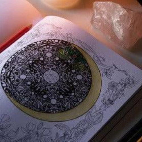 Decorative plate with intricate design on a book, next to a crystal.