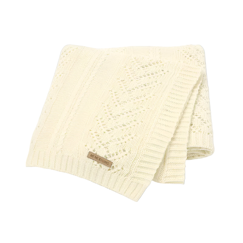 Cream-colored knitted blanket with a brand label on a white background