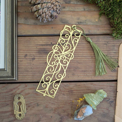Decorative gold bookmark with tassel on a wooden surface with natural elements.