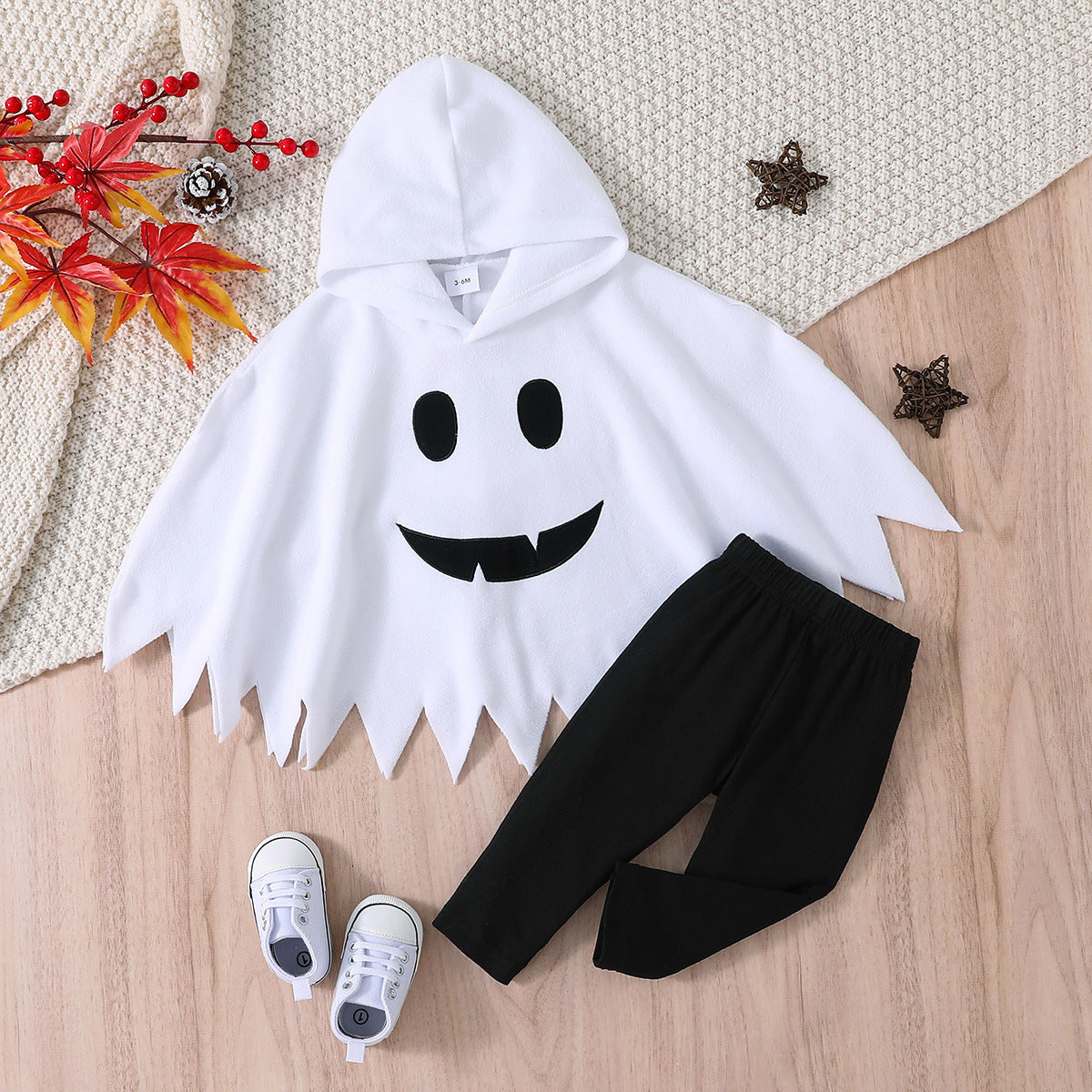 Ghost-themed outfit with a white hooded garment and black pants on a wooden surface.