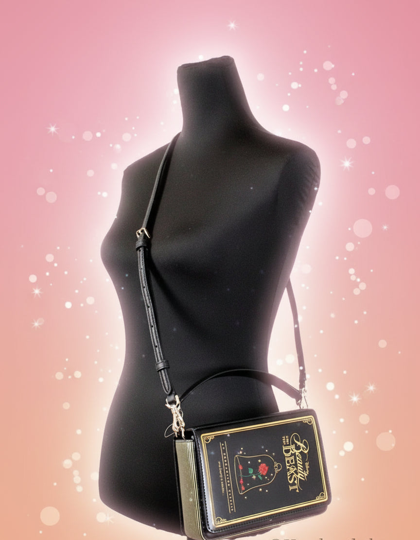 Black book-shaped handbag with gold accents on a mannequin against a white background