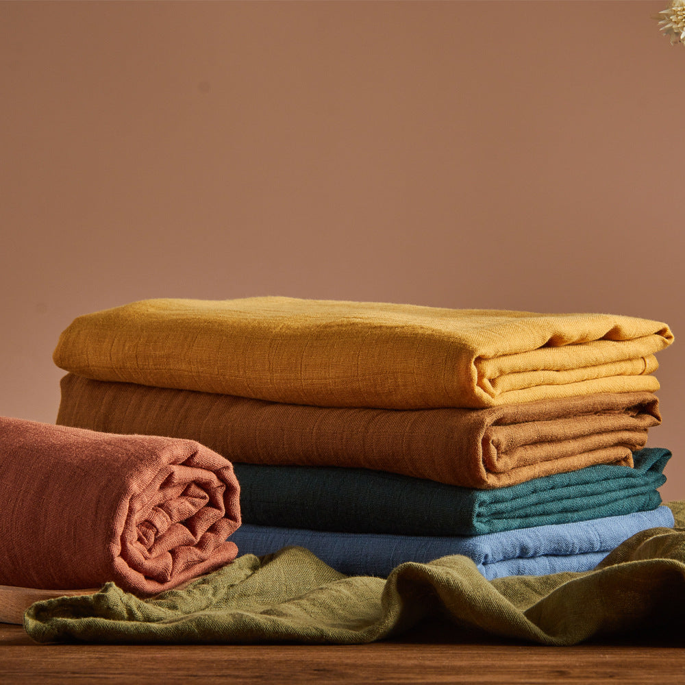 Stack of folded cloths in various colors on a wooden surface with a brown background