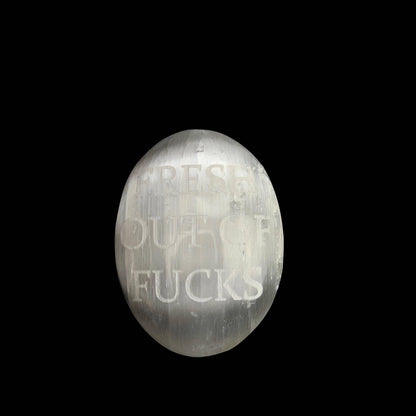 An oval-shaped, brushed-metal wall sign with the phrase 'FRESH OUT OF FUCKS' debossed on the front, shown against a solid black background.
