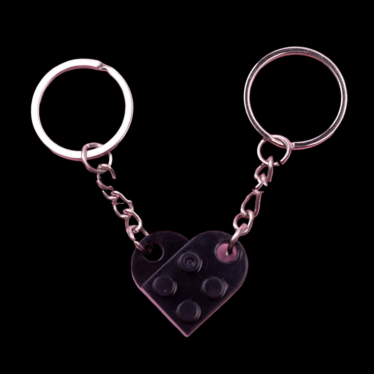 Black heart-shaped keychain with silver chain on pink background