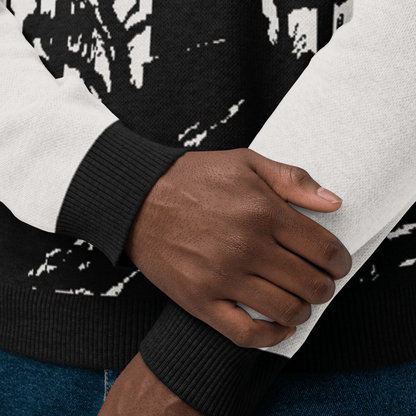 Close-up of a person wearing a black and white patterned sweater with a focus on the sleeve and hand.