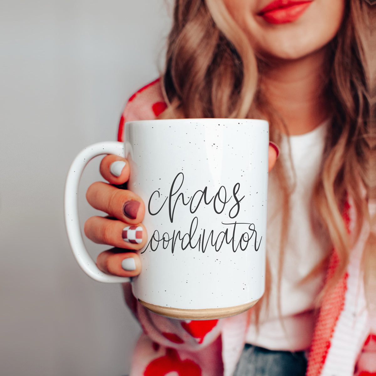 Person holding a white mug with 'chaos coordinator' text