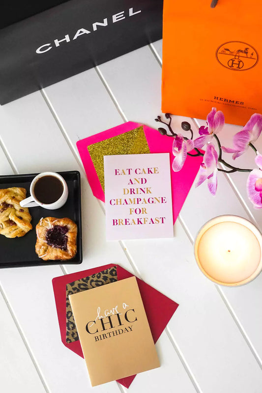 Greeting cards with text, a cup of coffee, pastries, and a candle on a white surface.