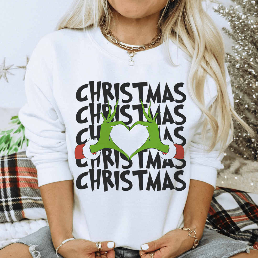 Person wearing a white sweatshirt with 'Christmas' text and green heart design.