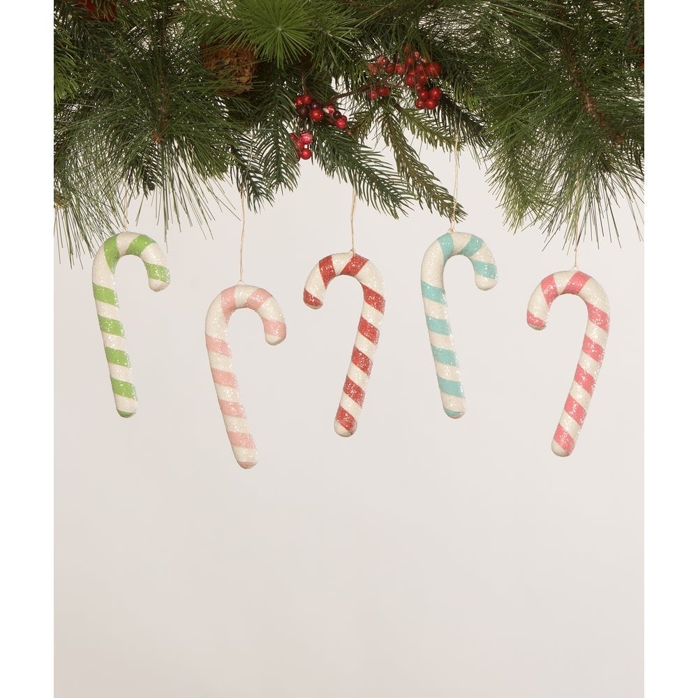 Set of candy cane-shaped Christmas ornaments hanging from a branch with greenery.