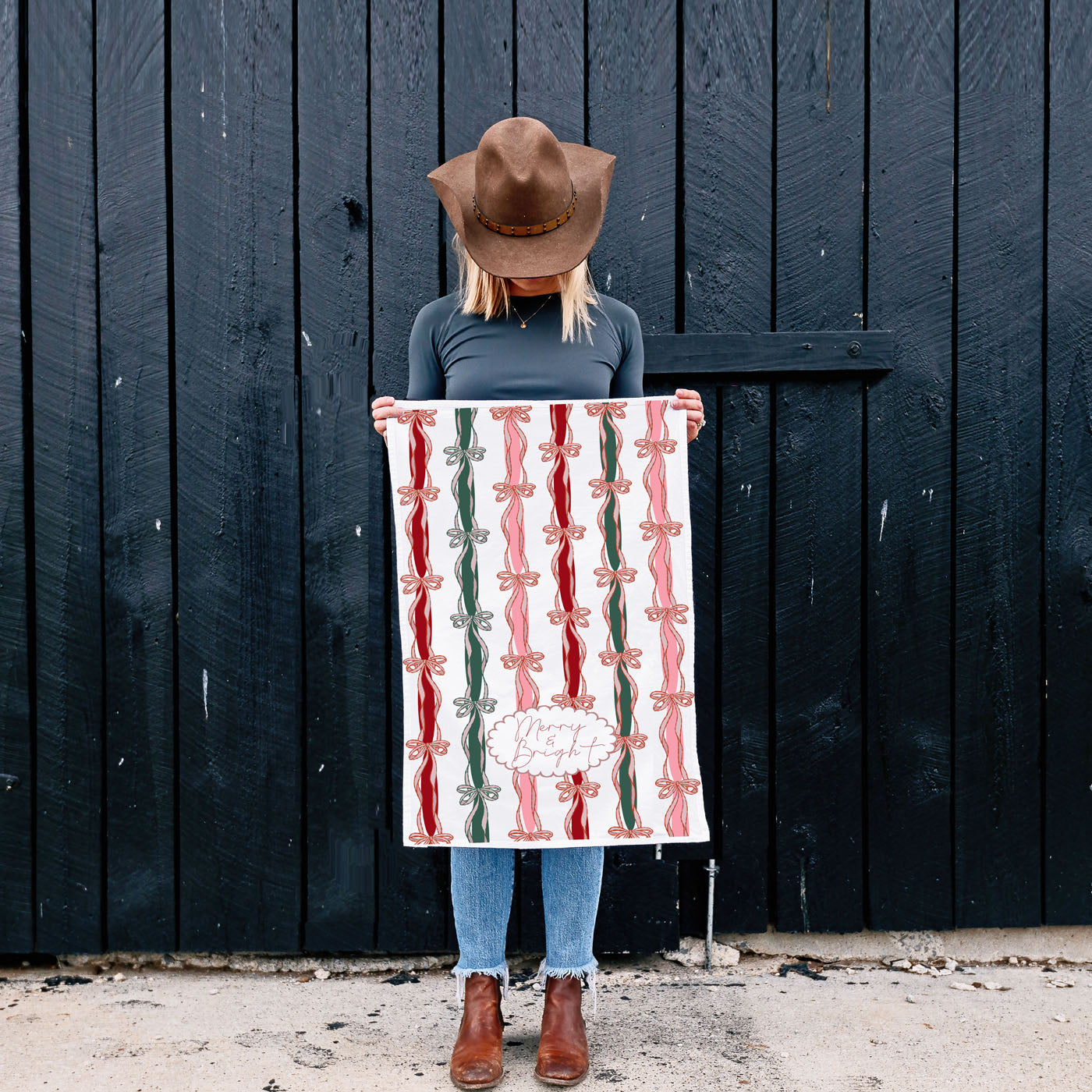 Person holding a decorative blanket with a black wooden door in the background