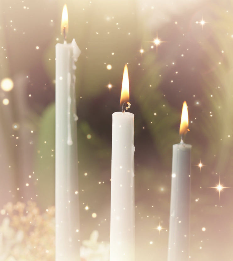 Three lit candles of different colors against a blurred green background