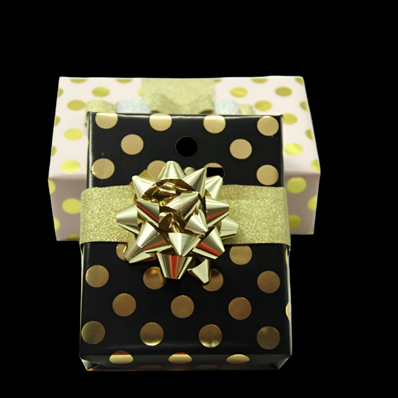 Gift box with gold polka dots and a gold bow on a white background