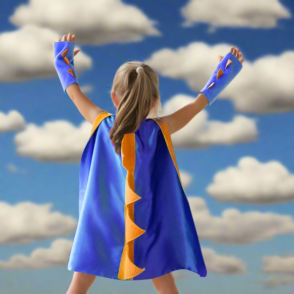 Child wearing a blue superhero cape with orange accents outdoors.