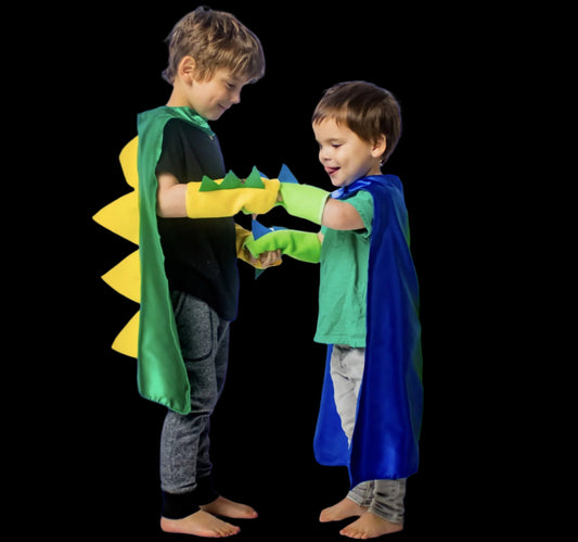 Two children in dinosaur-themed superhero costumes standing against a plain background
