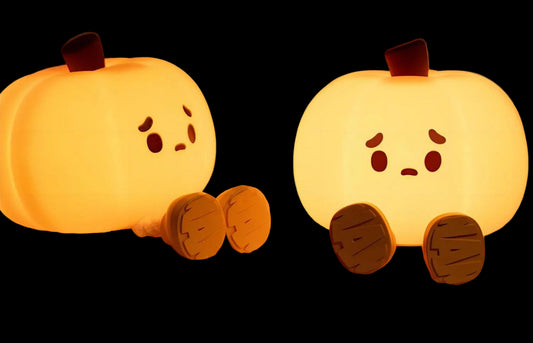 Two pumpkin-shaped night lights emitting a soft warm light on a neutral background.