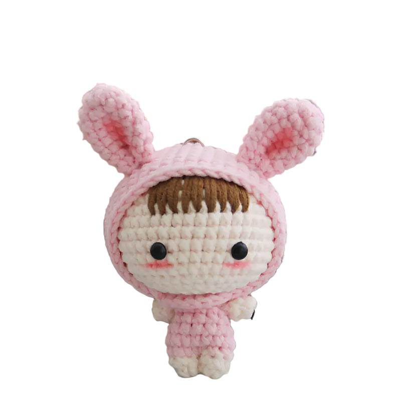 Pink crochet doll with bunny ears on a wooden shelf background
