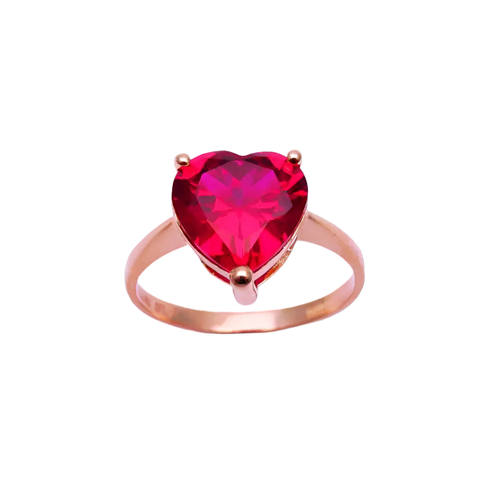 Rose gold ring with a heart-shaped red gemstone on a light purple background