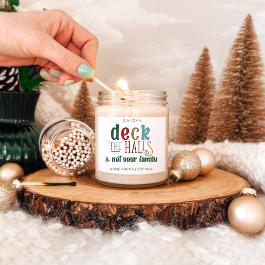 Candle being lit with a decorative label on a wooden surface with Christmas decor.