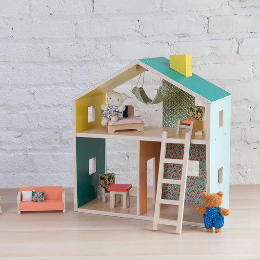 Wooden dollhouse with furniture and toys against a white brick wall.