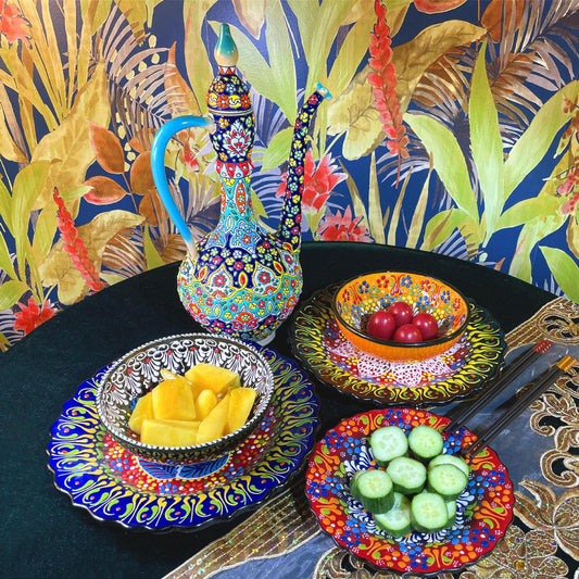 Colorful ceramic dishes with fruit on a table against a floral background