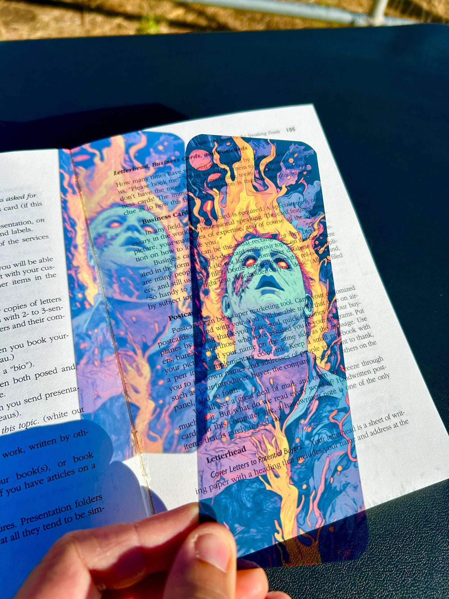Colorful bookmark with a character design held over a book