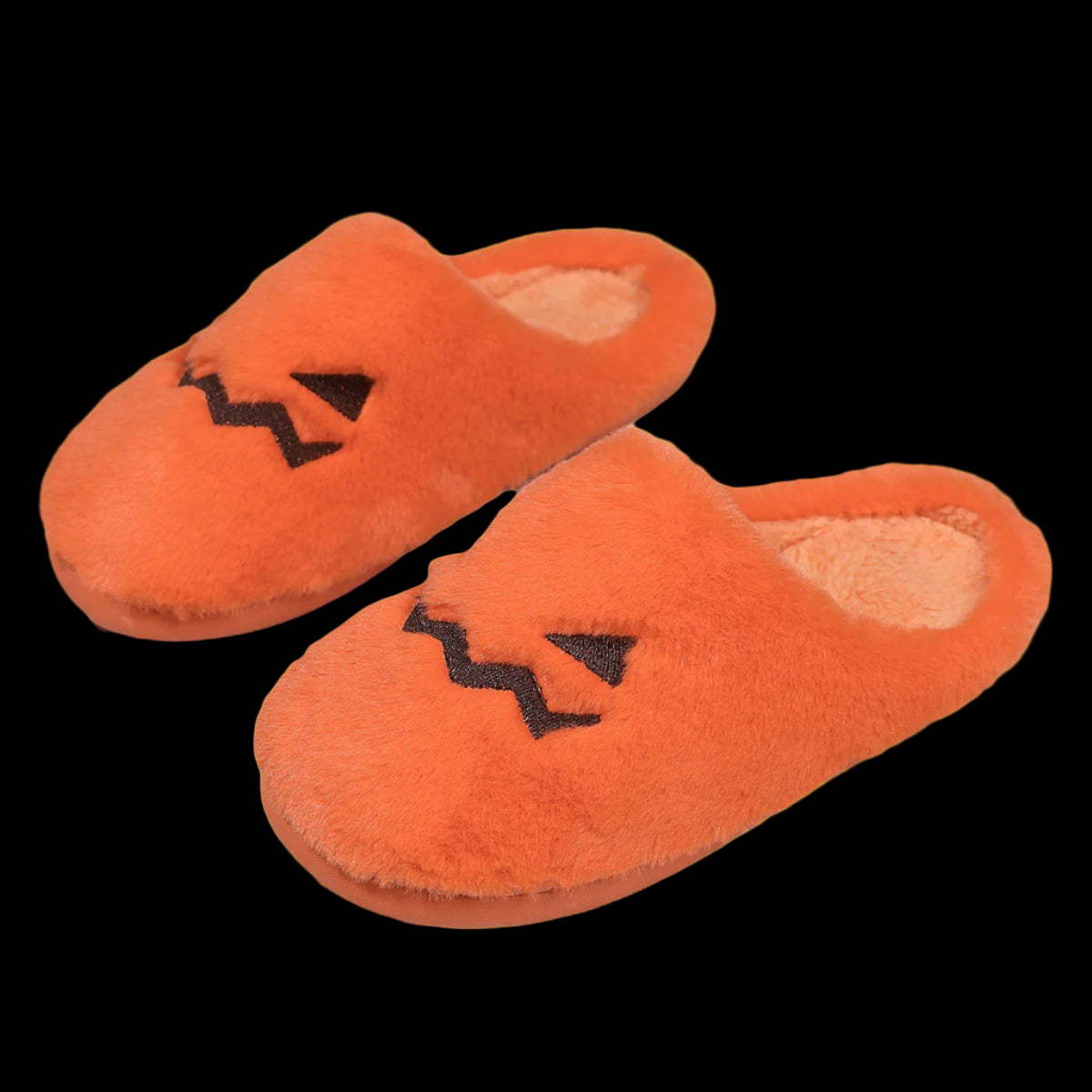 Pair of orange slippers with jack-o'-lantern faces on a white background