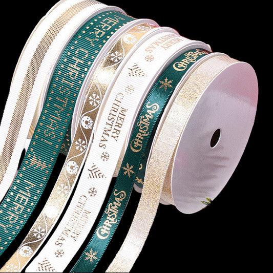 Collection of Christmas-themed ribbons with decorative boxes and greenery in the background.