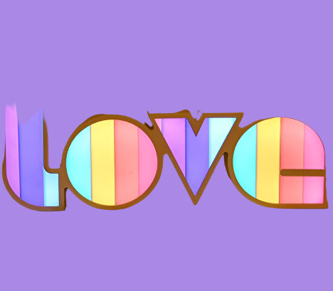 Colorful 'LOVE' sign on a wooden surface with a warm background