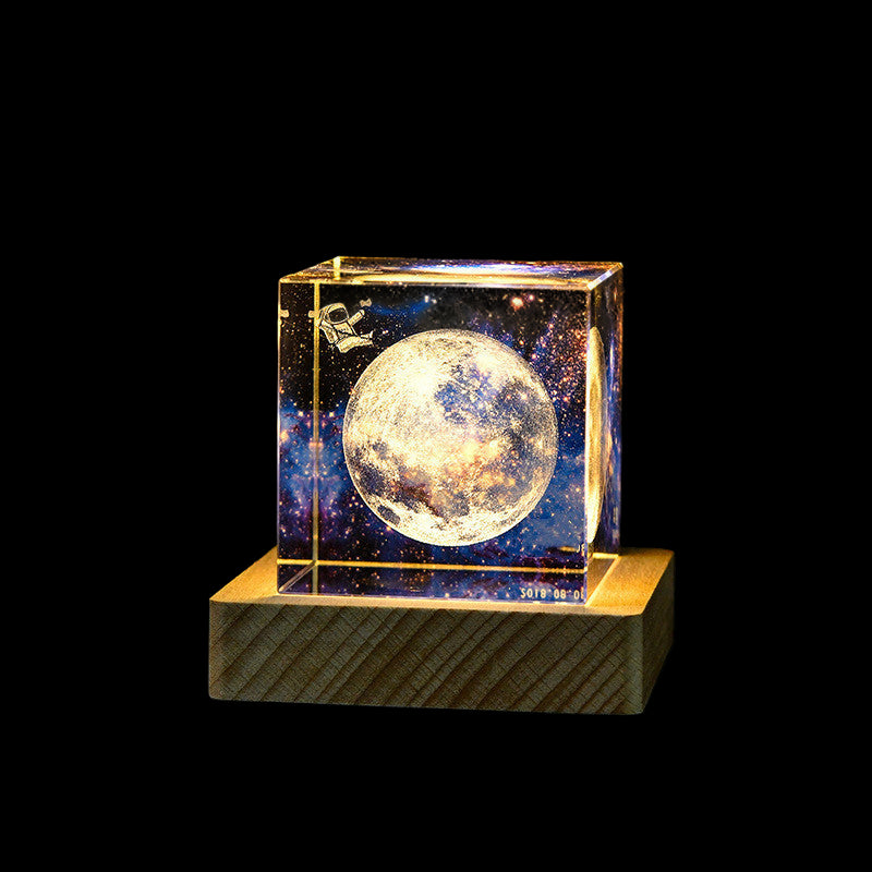 Cubical light with moon design on a wooden base against a dark background