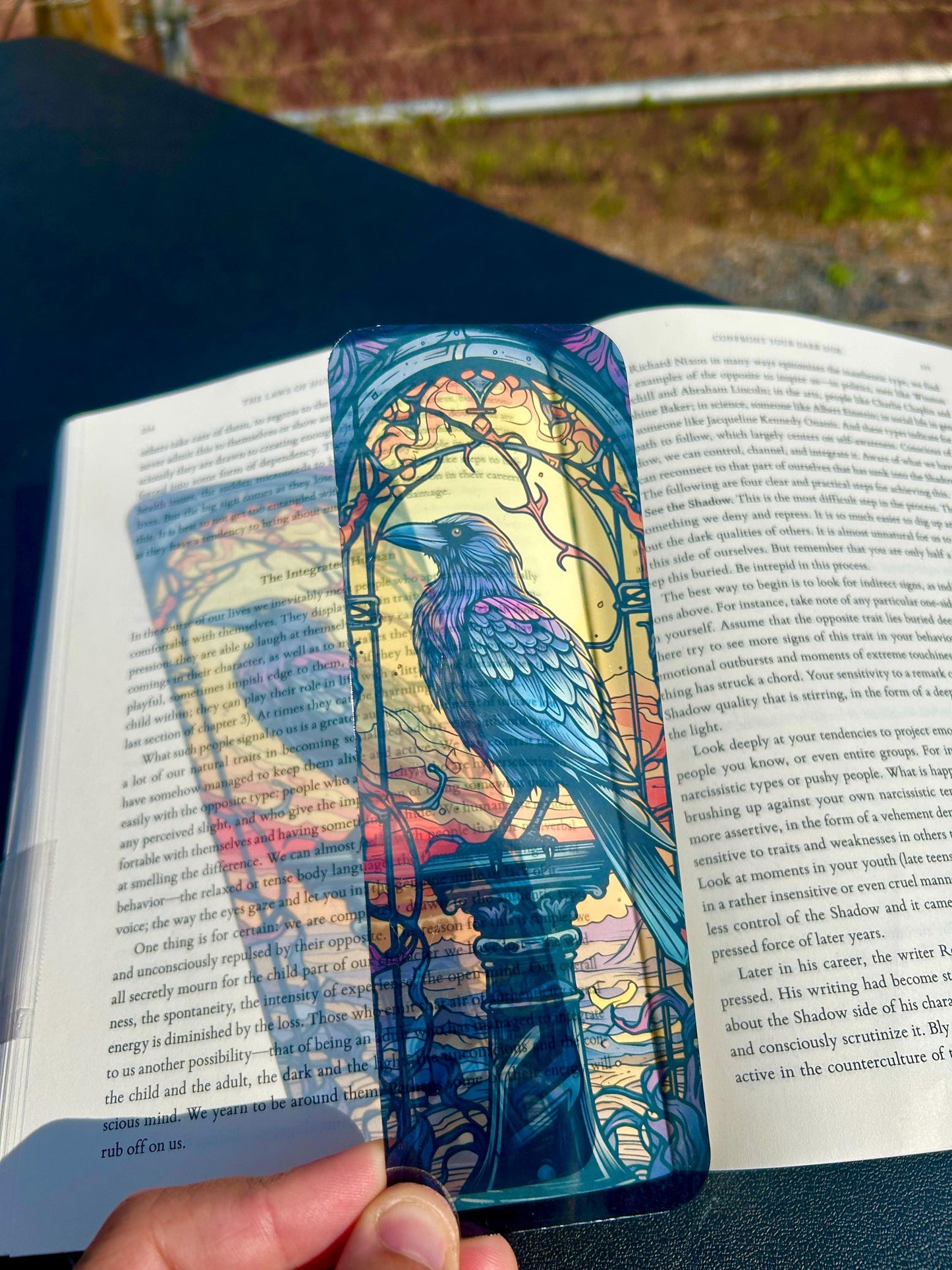 Colorful bird-themed bookmark on an open book outdoors