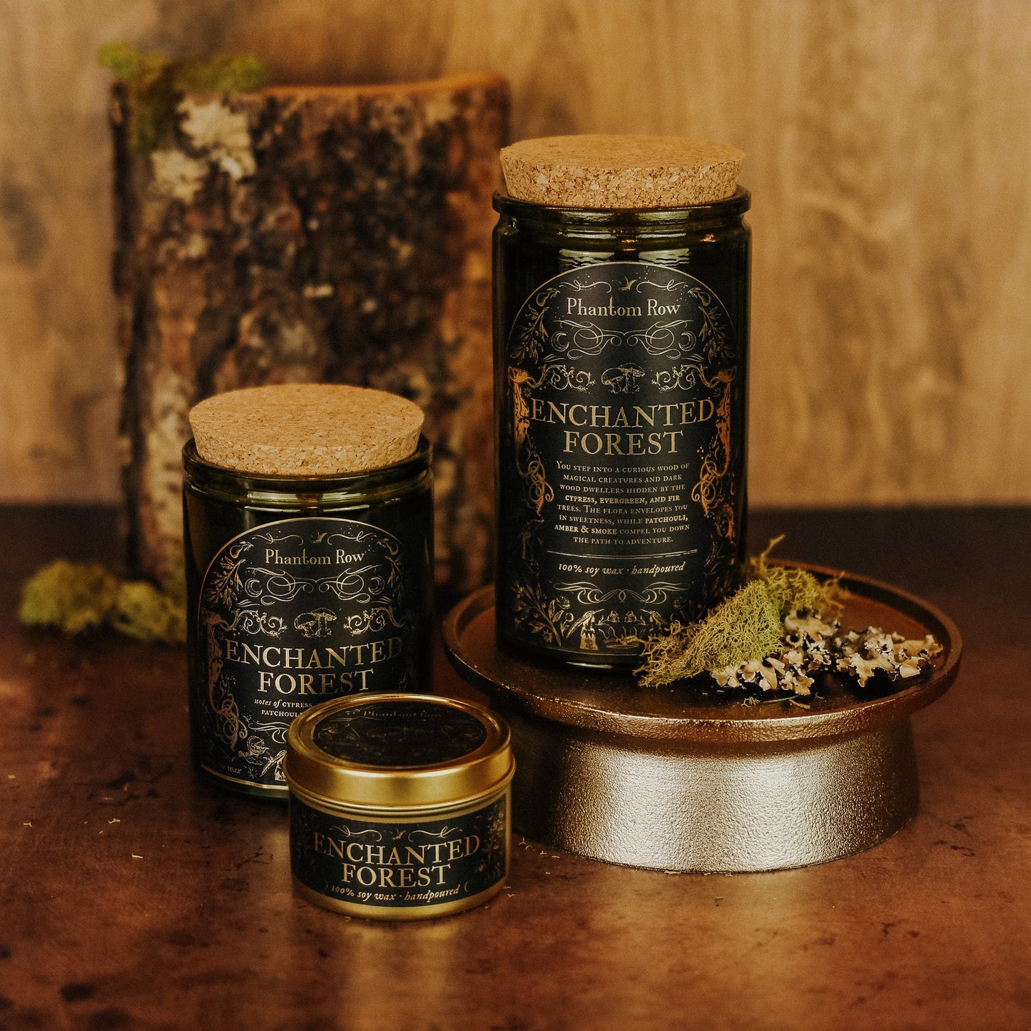 Three 'Enchanted Forest' candles on a wooden surface with a rustic background.